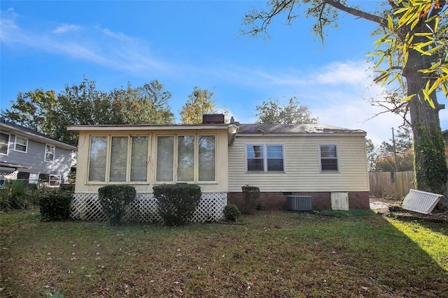 rear view of house featuring central air condition unit, a lawn, and a sunroom