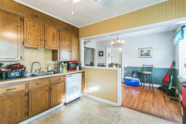 kitchen featuring pendant lighting, white dishwasher, crown molding, sink, and a notable chandelier