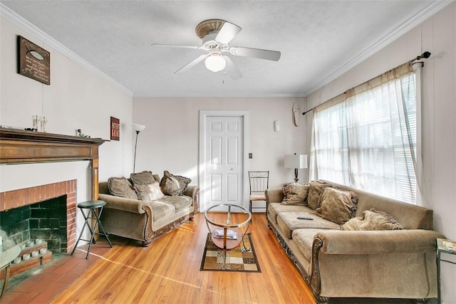 living room featuring ceiling fan, ornamental molding, a textured ceiling, and a brick fireplace