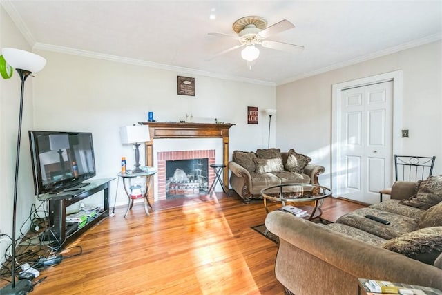 living room featuring hardwood / wood-style floors, a brick fireplace, ceiling fan, and crown molding