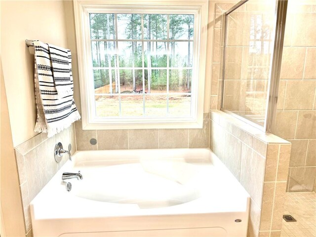 bathroom with a tile shower and a bath