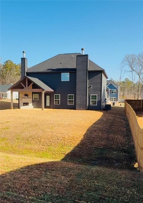 rear view of property featuring a lawn and a chimney