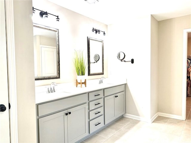 bathroom with double vanity, tile patterned floors, a sink, and baseboards