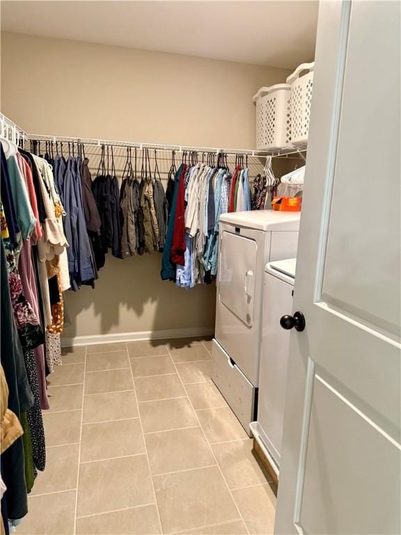 walk in closet with washing machine and clothes dryer and light tile patterned floors