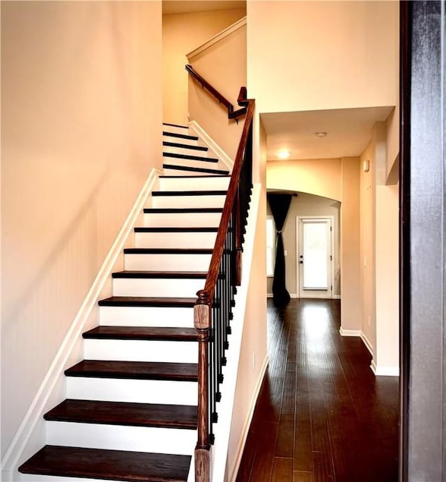 stairway with a high ceiling, baseboards, and hardwood / wood-style floors