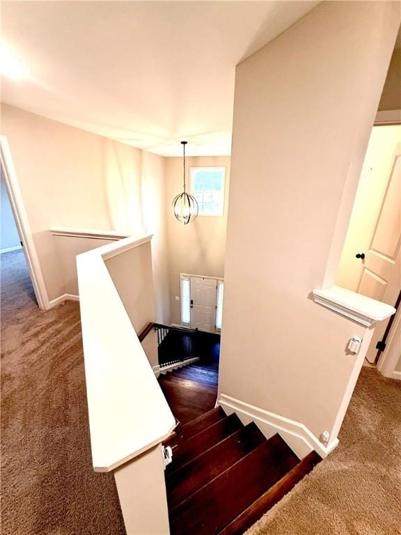 staircase featuring baseboards, carpet flooring, and a notable chandelier