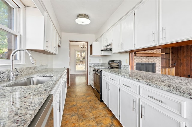 kitchen featuring black electric range, white cabinets, light stone counters, and sink