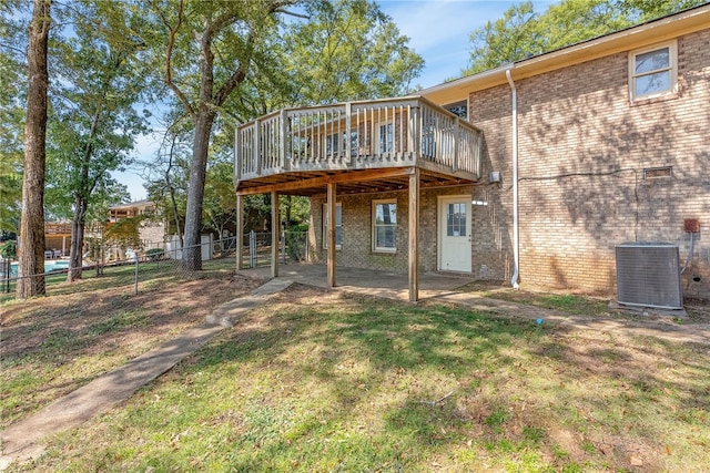 rear view of house with a lawn, a wooden deck, and cooling unit