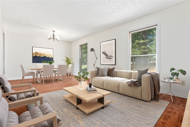 living room with hardwood / wood-style floors, a textured ceiling, and an inviting chandelier