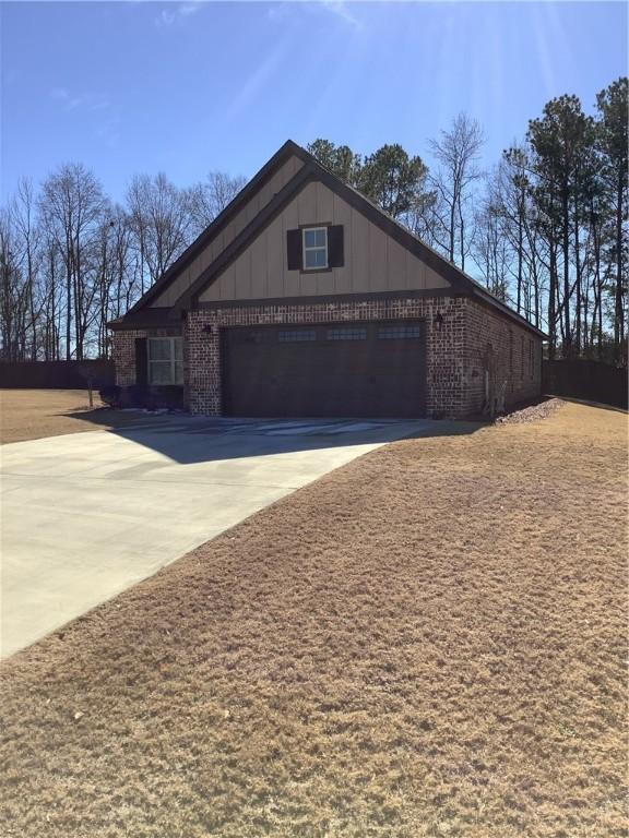 view of home's exterior with concrete driveway, a garage, board and batten siding, and brick siding