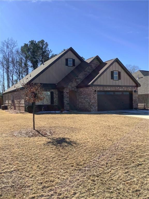 view of front of property with concrete driveway, board and batten siding, brick siding, and a garage
