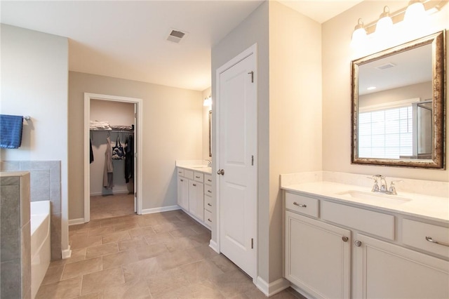 2647 Dunkirk Cir, Auburn, AL 36832 - bathroom featuring two vanities, a bath, a spacious closet, and baseboards