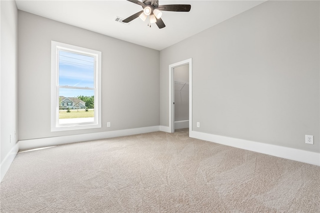 carpeted empty room with a ceiling fan, visible vents, and baseboards