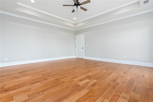 unfurnished room featuring light wood-type flooring, baseboards, ornamental molding, and a raised ceiling