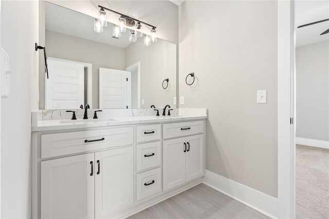 bathroom with double vanity, a sink, and baseboards