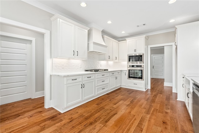 kitchen featuring stainless steel appliances, light countertops, custom range hood, and tasteful backsplash