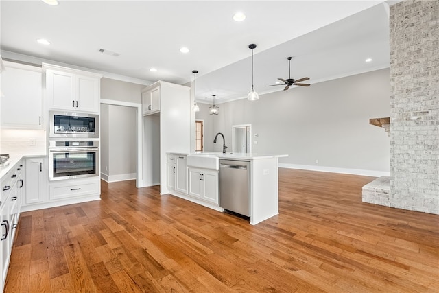 kitchen featuring light wood finished floors, visible vents, appliances with stainless steel finishes, open floor plan, and a sink