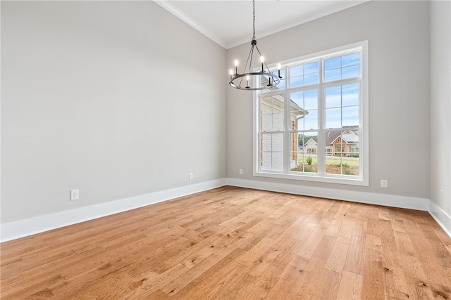 unfurnished dining area featuring ornamental molding, light wood-style flooring, baseboards, and an inviting chandelier