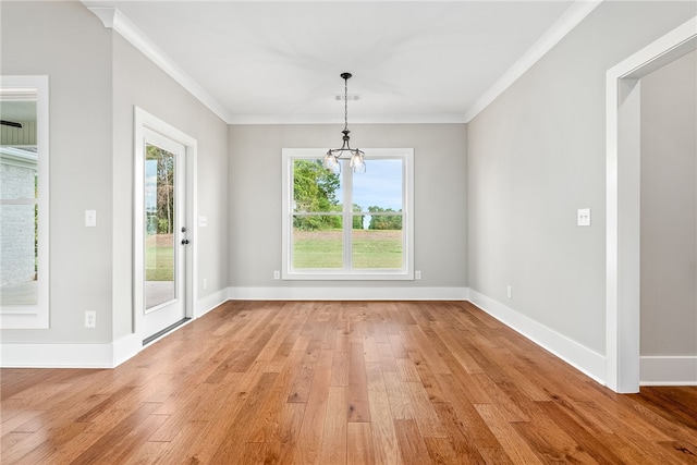 unfurnished dining area with baseboards, light wood finished floors, a notable chandelier, and crown molding