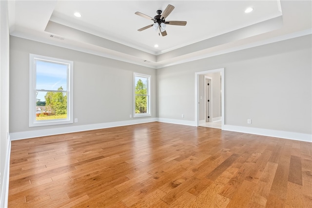 empty room featuring recessed lighting, a raised ceiling, ceiling fan, light wood-type flooring, and baseboards