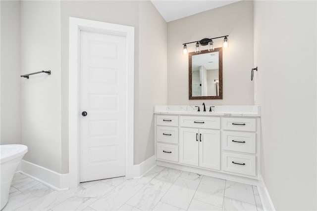 full bathroom with marble finish floor, baseboards, a freestanding bath, and vanity