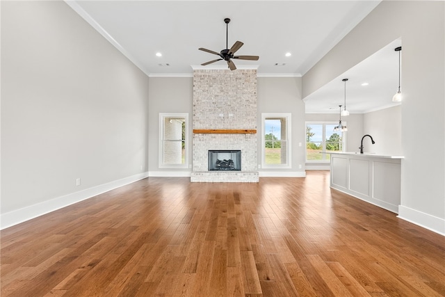 unfurnished living room featuring ornamental molding, a brick fireplace, baseboards, and light wood finished floors