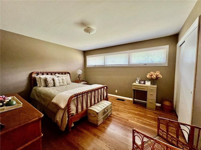 bedroom with visible vents, wood finished floors, and multiple windows