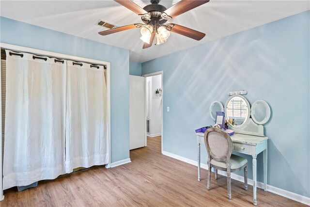 interior space with baseboards, a ceiling fan, wood finished floors, and visible vents