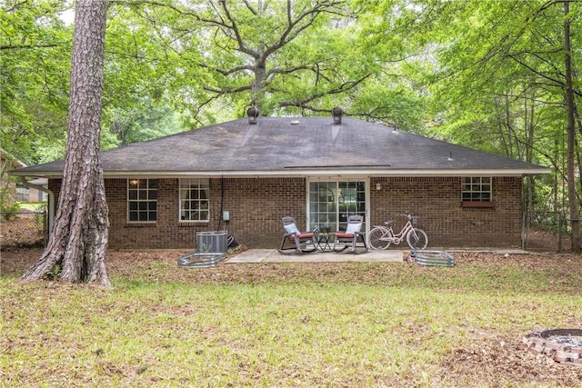 rear view of property featuring a lawn, brick siding, a patio area, and central air condition unit