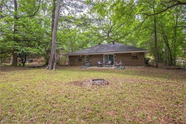 rear view of house featuring an outdoor fire pit, brick siding, a fenced backyard, a patio, and a yard