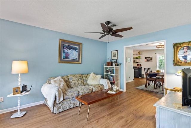 living room featuring a ceiling fan, baseboards, visible vents, and wood finished floors