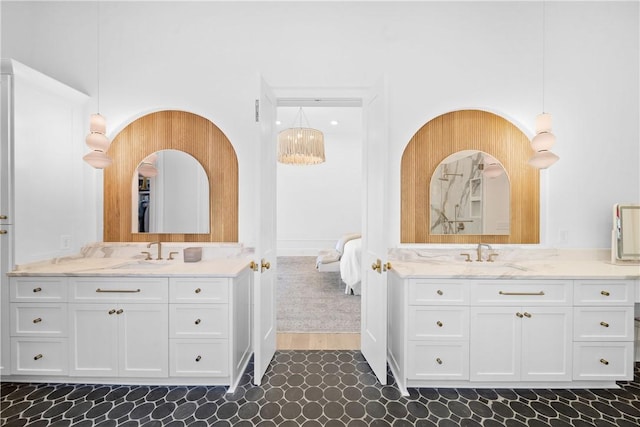 bathroom with two vanities, a sink, and ensuite bathroom