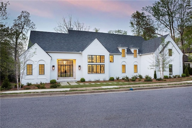 french country style house with a chimney and a shingled roof