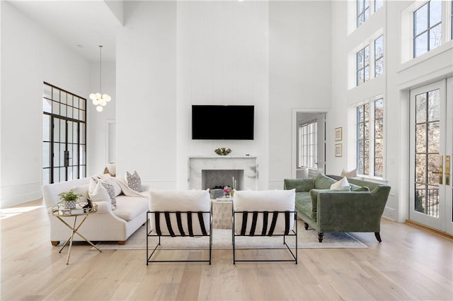 living room with a premium fireplace, wood finished floors, a wealth of natural light, and a notable chandelier