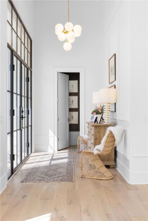 living area featuring a chandelier, baseboards, a high ceiling, and wood finished floors