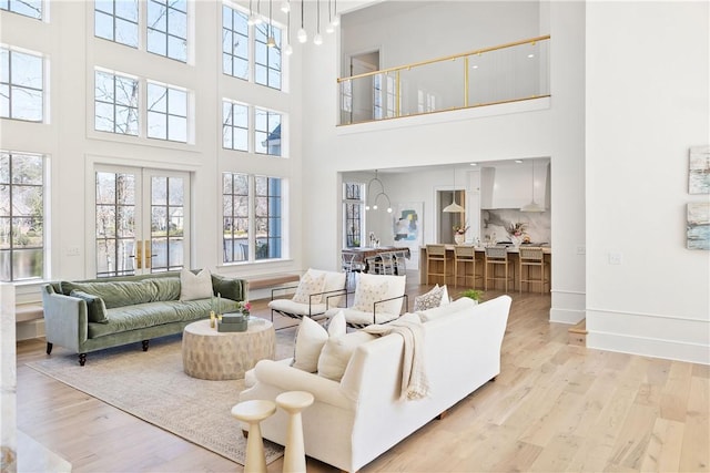 living area featuring french doors, baseboards, and light wood finished floors