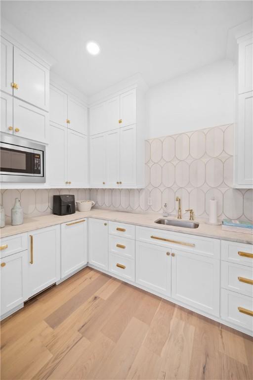 kitchen with white cabinets, stainless steel microwave, light countertops, and a sink