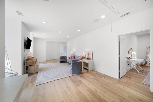 living room with light wood finished floors, recessed lighting, visible vents, and attic access