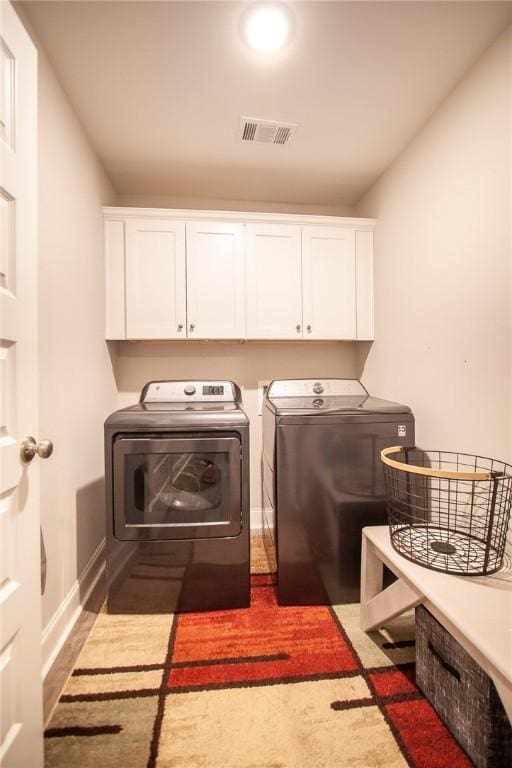 clothes washing area with cabinets and washing machine and clothes dryer