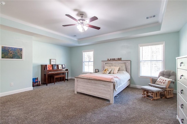 bedroom with ceiling fan, multiple windows, and a raised ceiling