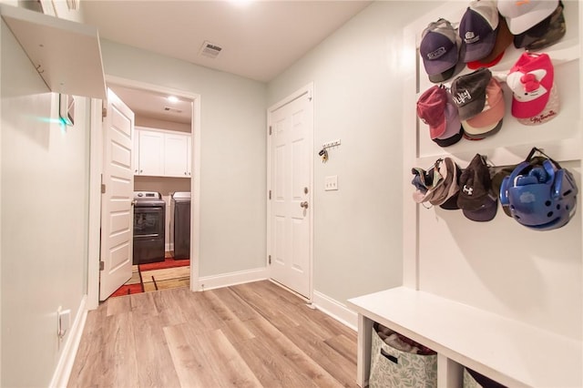 mudroom with light hardwood / wood-style floors and washing machine and dryer