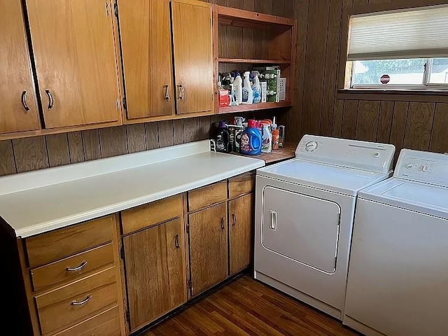 clothes washing area with wood walls, dark wood-type flooring, cabinets, and washer and dryer