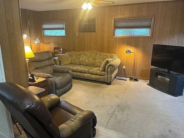 carpeted living room featuring ceiling fan and wood walls