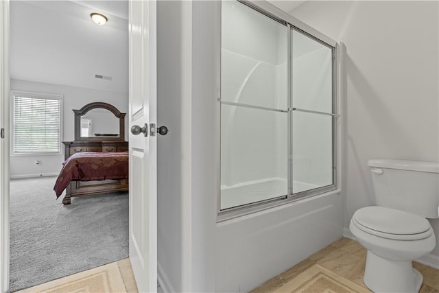 bathroom with toilet and shower / bath combination with glass door