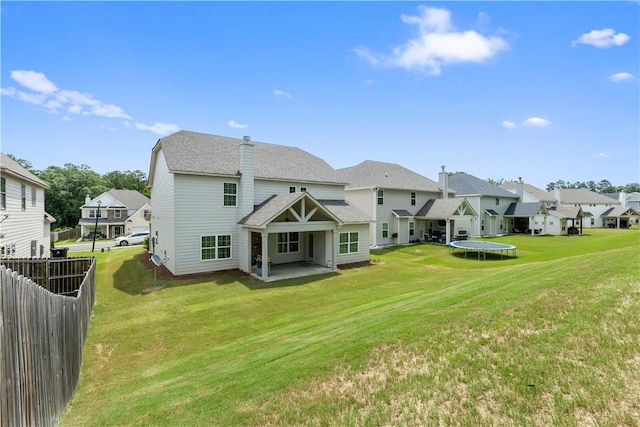 rear view of house with a lawn, a patio area, and a trampoline