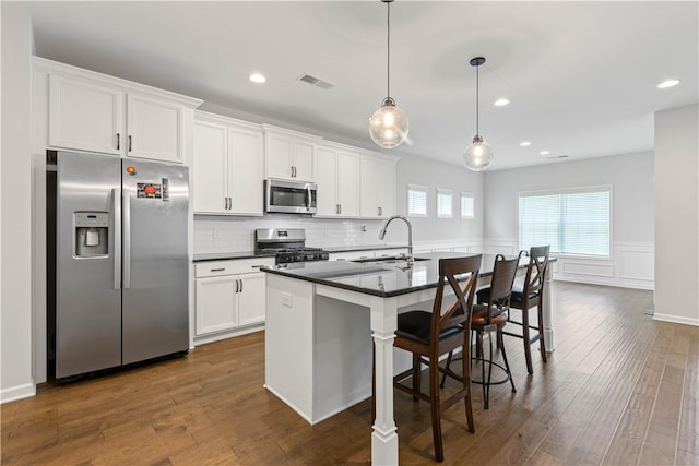 kitchen with white cabinets, a center island with sink, sink, and appliances with stainless steel finishes