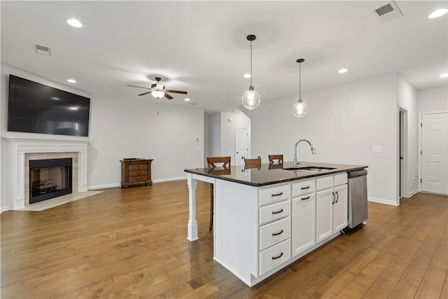 kitchen featuring ceiling fan, sink, hanging light fixtures, a kitchen island with sink, and white cabinets