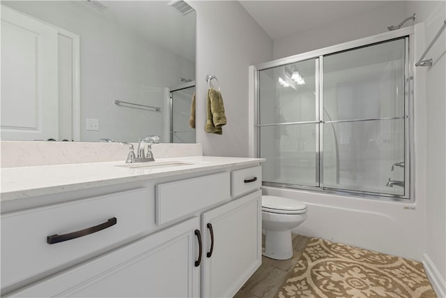 full bathroom with hardwood / wood-style flooring, vanity, toilet, and shower / bath combination with glass door