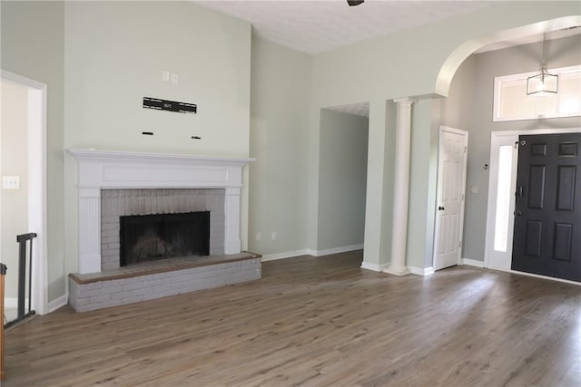 106 Pine Ridge Ln, Tallassee, AL 36078 - unfurnished living room with a towering ceiling, wood finished floors, a fireplace, and arched walkways