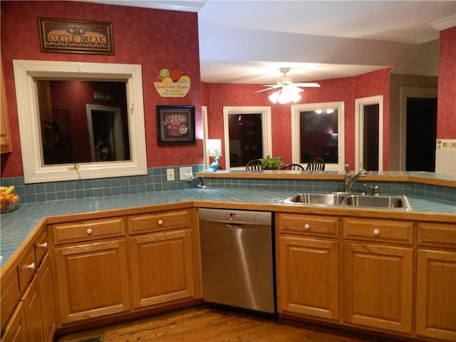 kitchen featuring tile countertops, dishwasher, sink, light wood-type flooring, and tasteful backsplash